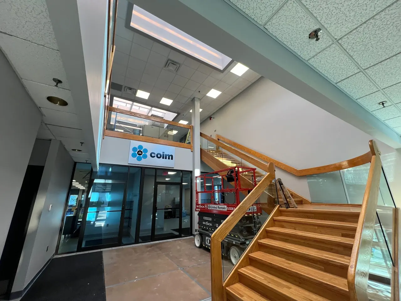 Lobby with wooden staircase and glass railing (COIM USA, West Deptford, NJ)