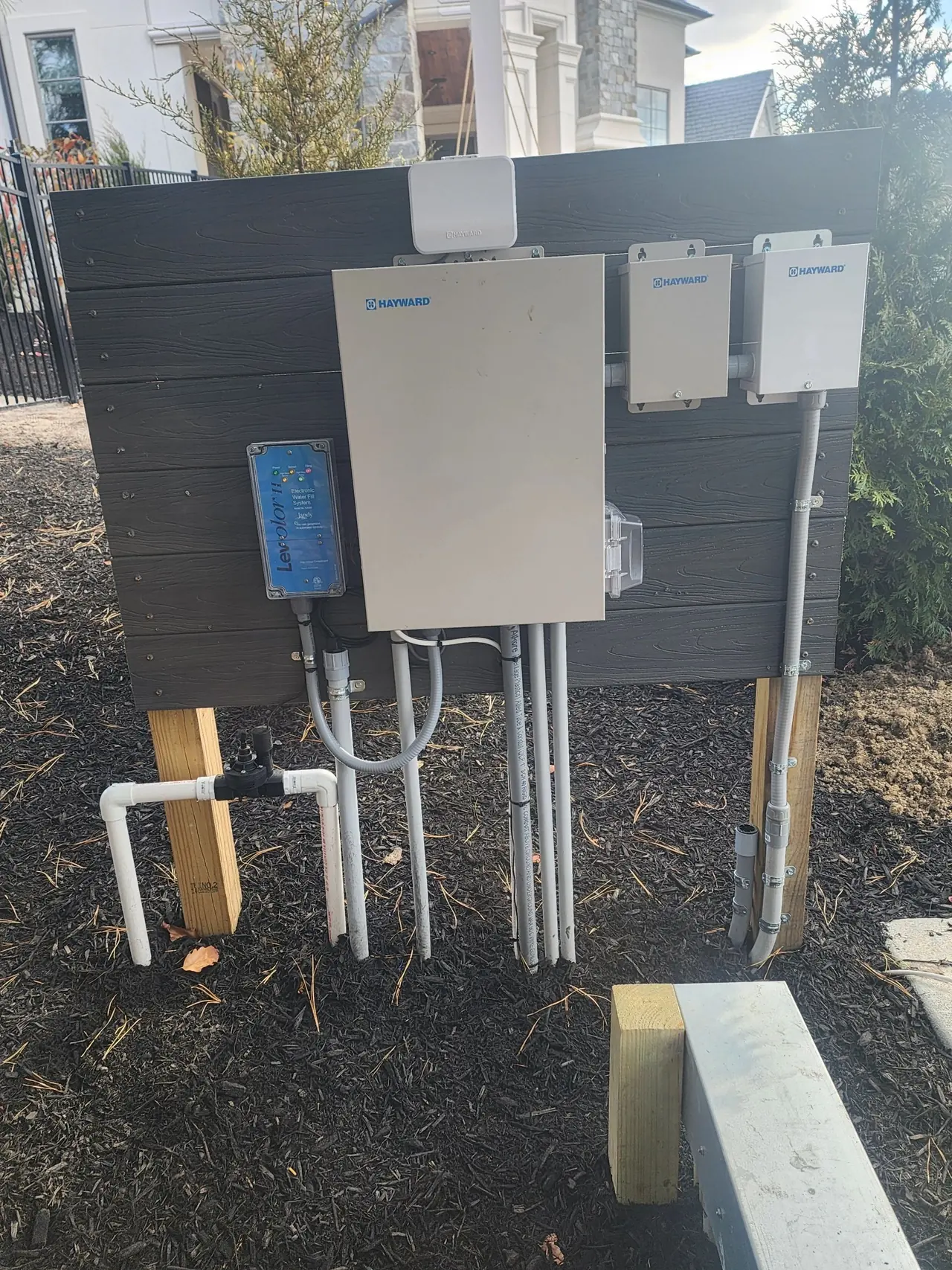 Pool equipment electrical enclosures mounted on a fence panel