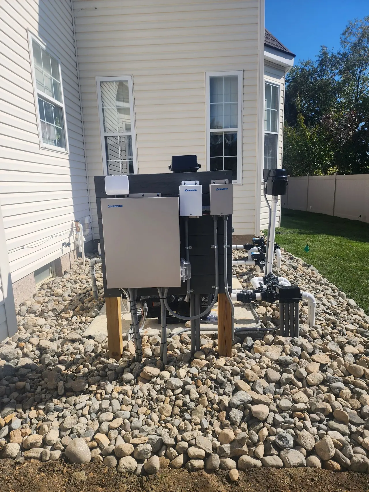 Pool equipment pad with electrical enclosures beside a home