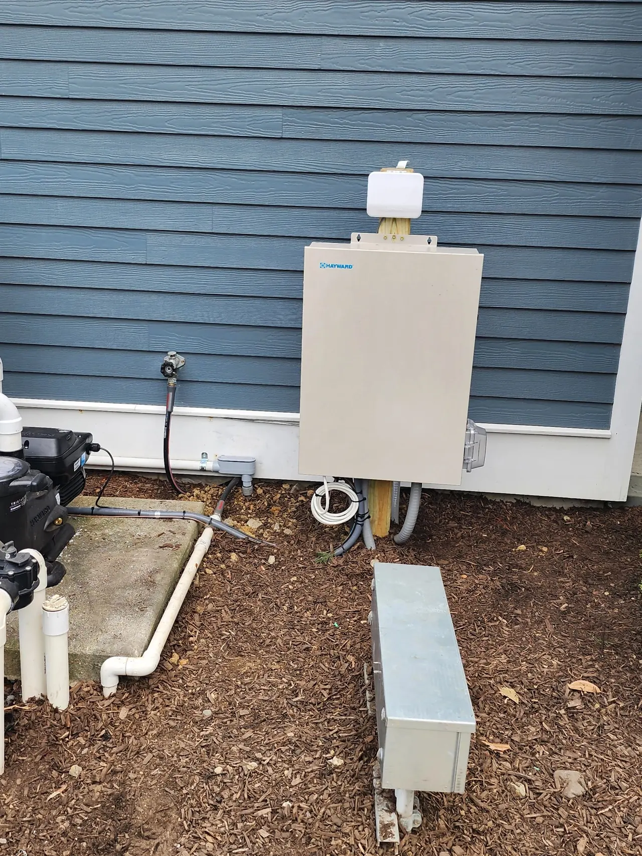 Pool automation enclosure mounted on the side of a house