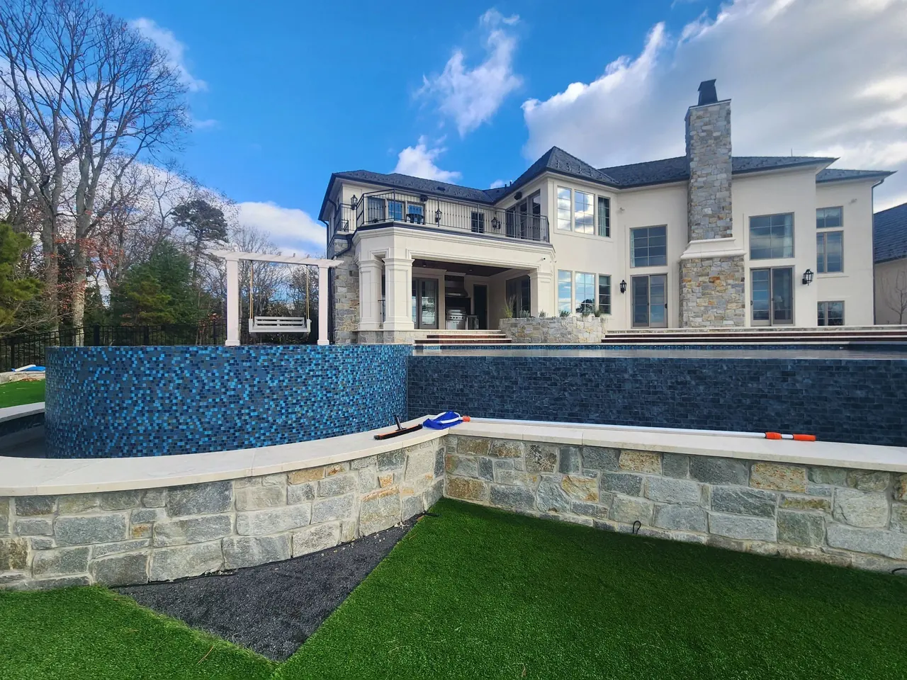 Spa wall and pool behind a large stone-trimmed home