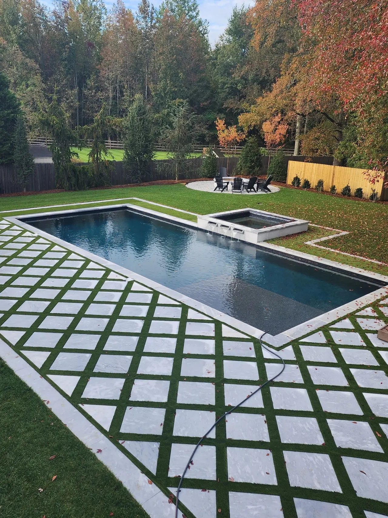 A rectangular pool surrounded by a paver and turf grid patio