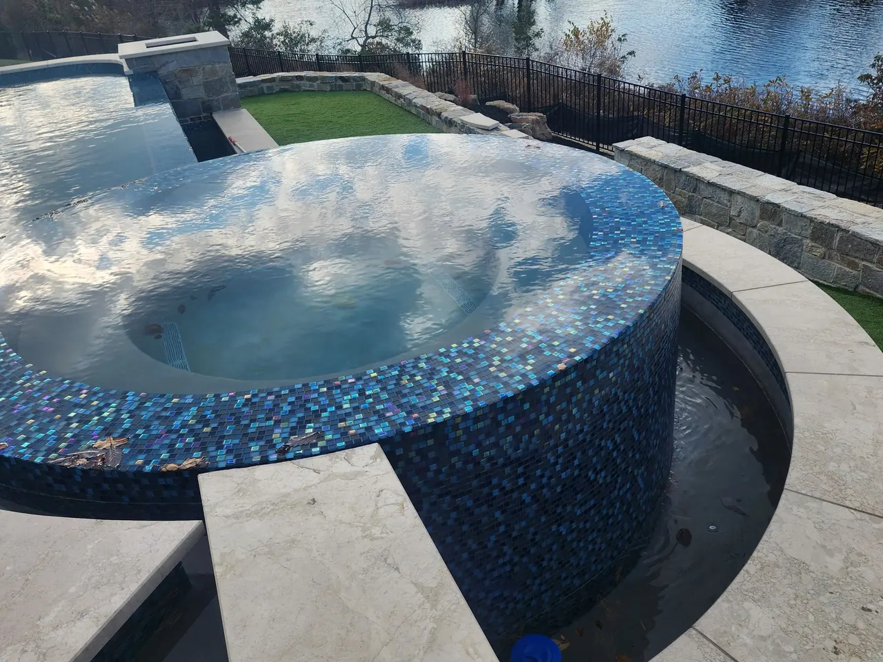 Raised spa with mosaic tile beside an infinity pool