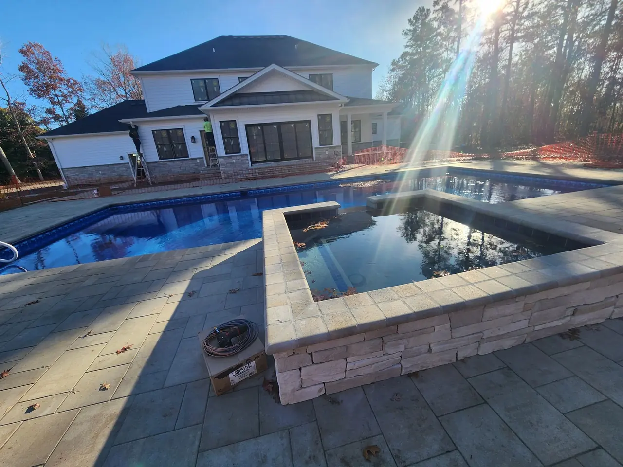 Pool and raised spa with stone coping on a sunny day